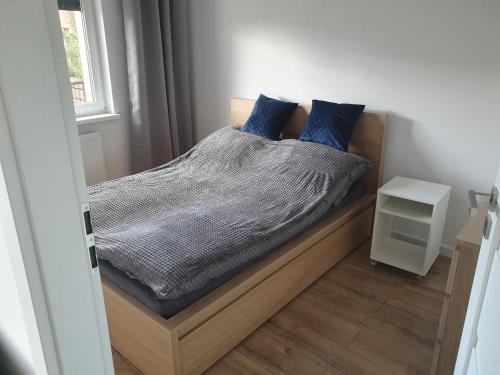 a bedroom with a bed with blue pillows on it at Good Time Apartaments Sienkiewicza in Leszno