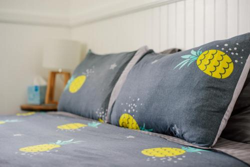 a bed with two pillows with pineapples on it at NEW - Pineapple Loft - Entire House Downtown Hilo with AC in Hilo