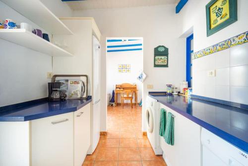 a kitchen with white cabinets and blue counter tops at FABULOUS BUNGALOW , WIFI, SWIMMING POOL AND BEACH in Pasito Blanco