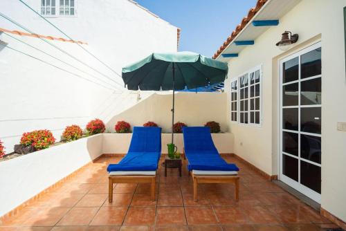 a patio with blue chairs and an umbrella at FABULOUS BUNGALOW , WIFI, SWIMMING POOL AND BEACH in Pasito Blanco