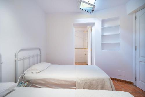 a white bedroom with two beds and a door at FABULOUS BUNGALOW , WIFI, SWIMMING POOL AND BEACH in Pasito Blanco