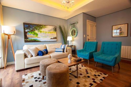 sala de estar con sofá y 2 sillas azules en Waldhaus 303 - My Home Temporada, en Gramado