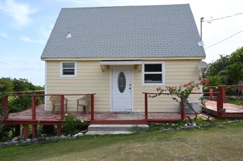 una pequeña casa amarilla con terraza de madera en Sea view Pointe, en Gregory Town