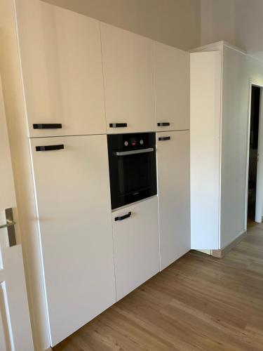 une cuisine avec des armoires blanches et un four noir dans l'établissement LE PETIT CLAVIER, à Lagord