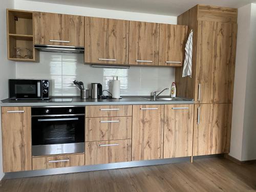a kitchen with wooden cabinets and a sink and a microwave at Usedlost Pivoňka in Mnichov