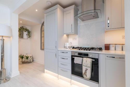 a kitchen with white cabinets and an oven at Central Apartment - with Patio and Sofa Bed! in Cheltenham