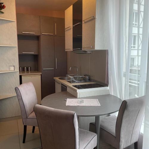 eine Küche mit einem Tisch und Stühlen sowie eine Küche mit einem Waschbecken in der Unterkunft Kopaonik apartmani u Kraljevim Čardacima , Čar 27 i 6-13 in Kopaonik
