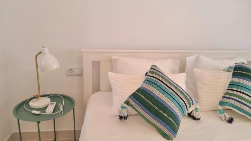 a bed with white pillows and a phone on a table at Apartamentos de la Huerta in Alicante
