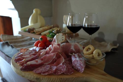a wooden cutting board with meat and two glasses of wine at La Cascina Nel Bosco in Faicchio