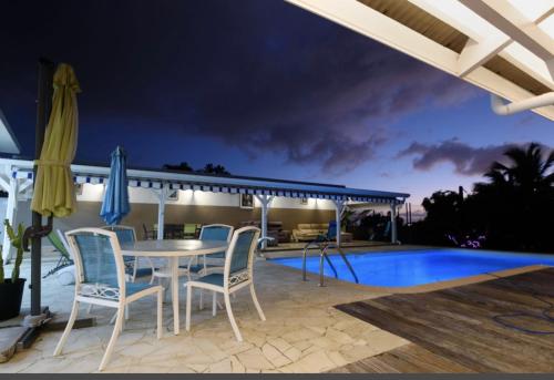 a patio with a table and chairs next to a swimming pool at Appartement avec vue sur la mer à Fort-de-France - 27 m² - Piscine in Fort-de-France