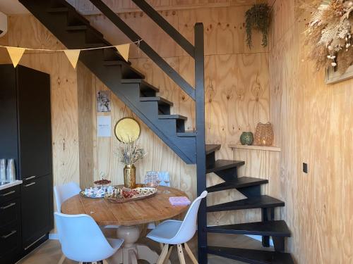 een eetkamer met een tafel en een trap bij Tiny House Thuus in Sint Annaland