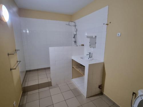 La salle de bains blanche est pourvue d'un lavabo et d'une douche. dans l'établissement Magnifique Villa Riad avec piscine proche plage, à Saly Portudal