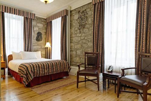 a hotel room with a bed and two chairs at Hôtel Manoir de l'Esplanade in Quebec City