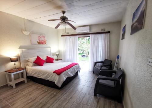 a bedroom with a bed and two chairs and a ceiling fan at Eden Wilds Unit 48 & 47 & 31 in Port Edward