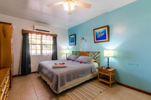 a bedroom with blue walls and a bed with two lamps at Miramar Suites in Placencia Village