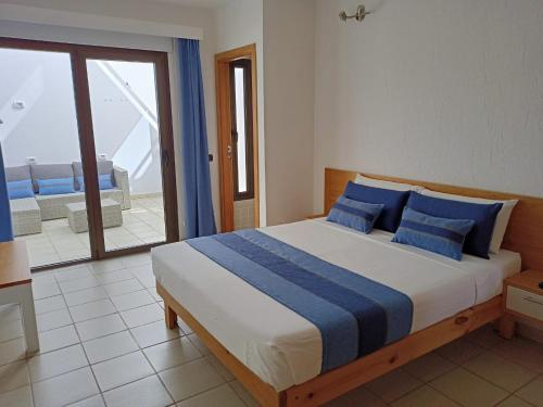 a bedroom with a bed with blue pillows and a balcony at Apartamento (Cotillo Mar) con vistas al Mar in Cotillo