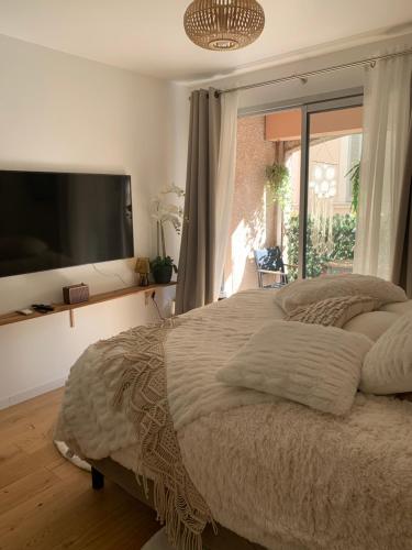 a bedroom with a large bed and a flat screen tv at Studio tt confort coeur ville avec terrasse et parking gratuit in Sanary-sur-Mer