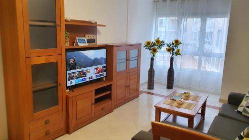 ein Wohnzimmer mit einem TV in einem hölzernen Unterhaltungszentrum in der Unterkunft Os Castelos Playa de Covas in Viveiro