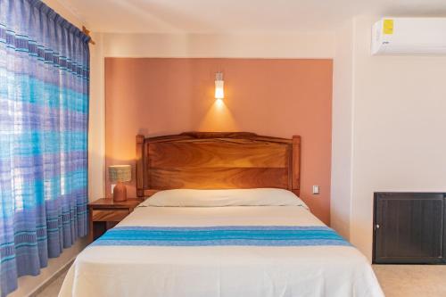 a bedroom with a bed with a wooden headboard and a window at Hotel El Mirador in Puerto Escondido