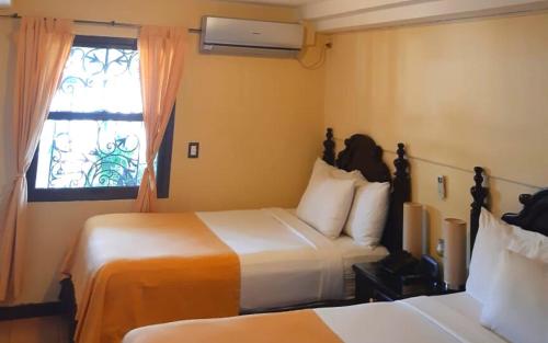 a hotel room with two beds and a window at Hotel Villa Florencia Zona Rosa in San Salvador