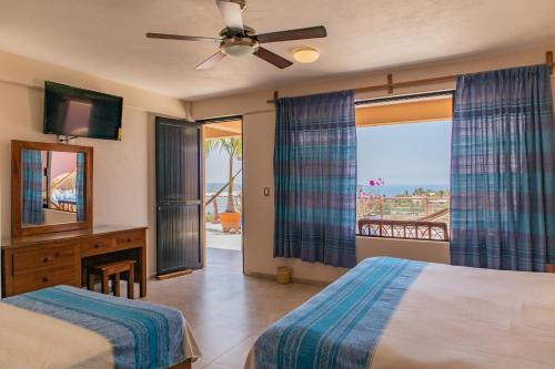 a bedroom with a bed and a window with a view at Hotel El Mirador in Puerto Escondido