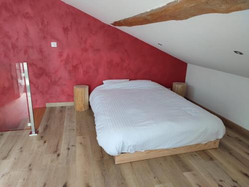 Cama en habitación con pared roja en Maison au calme dans un petit hameau, en Verdun-sur-Garonne