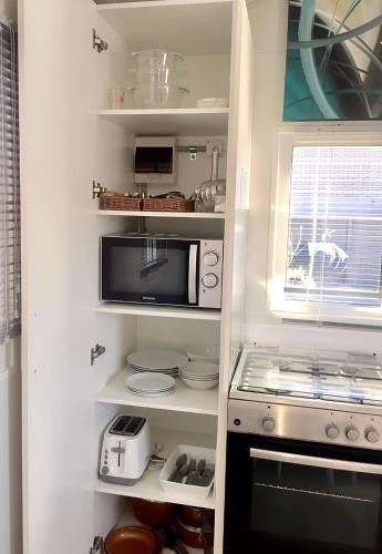 a kitchen with white shelves and a microwave at Almond Court Motel in Alexandra