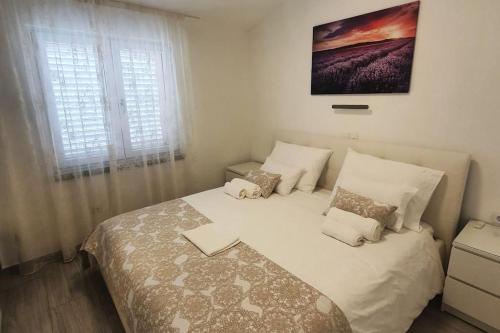 una camera da letto con letto, lenzuola e cuscini bianchi di Apartment Rosemary a Vela Luka (Vallegrande)