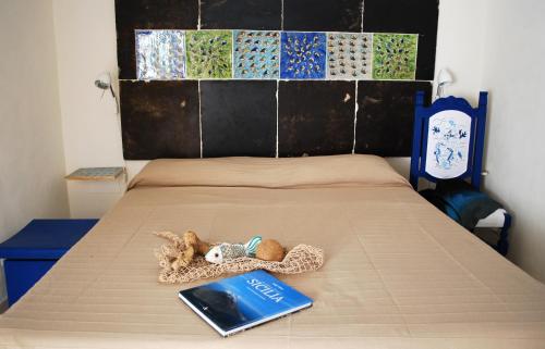 a bed with a book and a stuffed animal on it at Giulianna Uno in Donnalucata