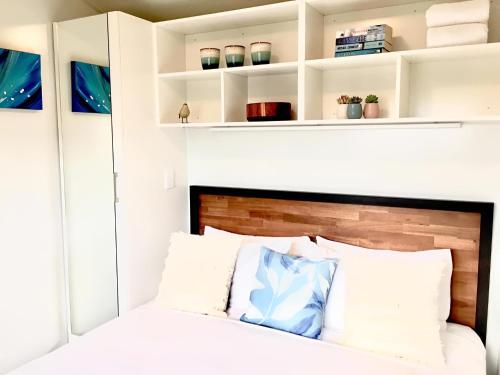 a bedroom with a bed with white walls and shelves at Almond Court Motel in Alexandra