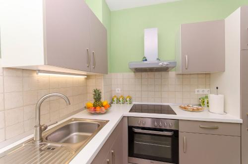 eine Küche mit weißen Schränken und einem Waschbecken in der Unterkunft Guest house LUCIJA with swimming pool in Tugare