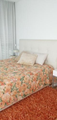 um quarto com uma cama com colcha floral em Ocean Village 10 em Grândola