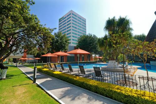 a pool with chairs and umbrellas and a building at Holiday Inn San Luis Potosi-Quijote by IHG in San Luis Potosí