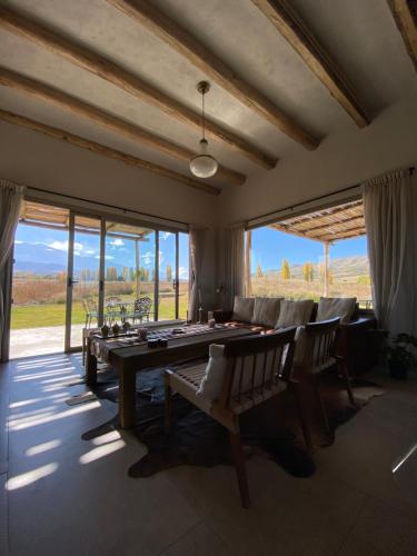 a large room with a table and chairs and windows at La Carrera Villas, Atamisque. Tupungato, Mendoza. in Ciudad Lujan de Cuyo