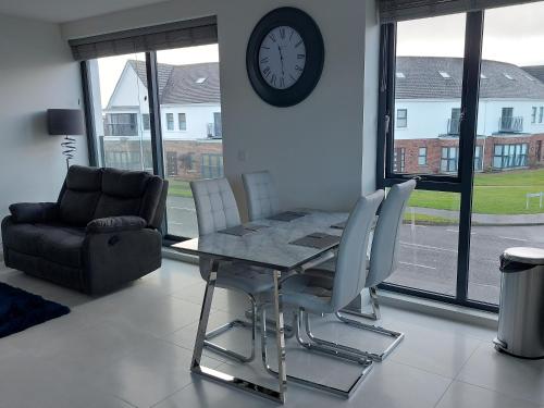 a dining room with a table and a clock on the wall at Portstewart Atlantic Cove Hatheran Gardens in Portstewart
