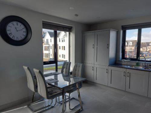 a dining room with a table and a clock on the wall at Portstewart Atlantic Cove Hatheran Gardens in Portstewart