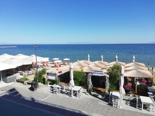 a beach with umbrellas and chairs and the ocean at Aktis Sea View Studios in Perea