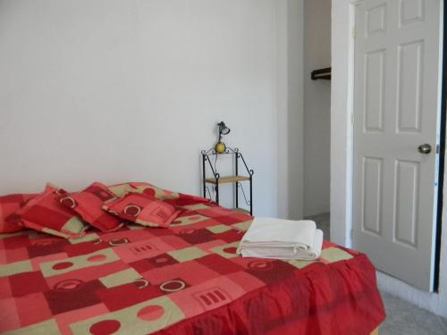 a bedroom with a bed with a red and yellow quilt at Hotel Lienzo Charro II in San Miguel Regla