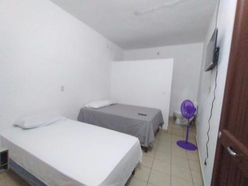 Habitación pequeña con 2 camas y TV. en Hotel Villa Aurora, en Flores