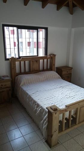 1 dormitorio con 1 cama de madera y 2 ventanas en DEPARTAMENTO 1 DORMITORIO en Mendoza