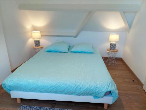 a bedroom with a bed with blue sheets and two lamps at Stone House in Brittany with Sea Views in Plonévez-Porzay