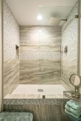 a bathroom with a shower with a large stone wall at Wine Country Pool Oasis for Couples or Groups in Temecula
