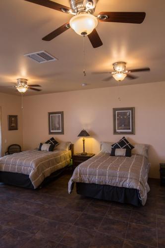 a bedroom with two beds and a ceiling fan at Turtle Back Mesa Bed and Breakfast in Indio
