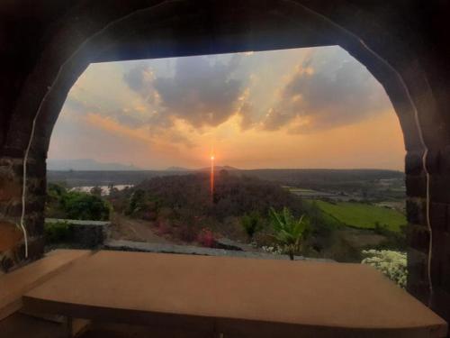 a view of the sunset from a window in a building at EZE NOF - A hilltop villa with 360º water view in Nashik