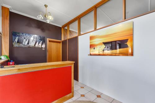 un vestíbulo con un mostrador rojo y pinturas en la pared en Robe Central Motel, en Robe