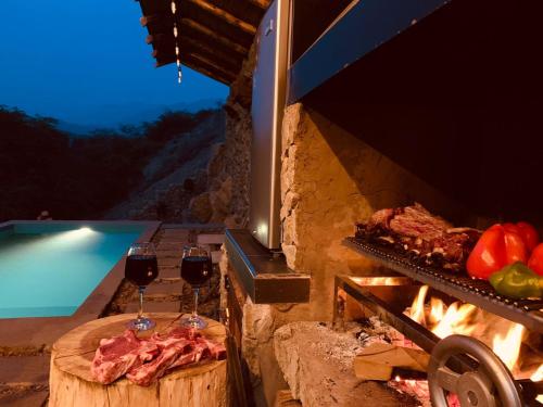 a grill with two glasses of red wine and meat at AYAR - Portentos & Cabañas QHAPAQ in Virú