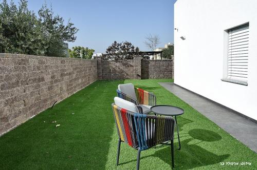 two chairs and a table on a lawn at סוויטה חדשה ויפהיפיה in Hagoshrim