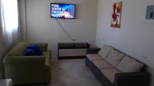 een woonkamer met een bank en een tv bij Apartamento Familiar frente a la Playa in Playas