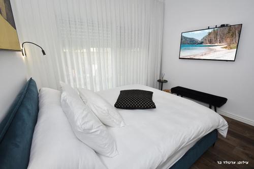 a bedroom with a bed with white sheets and pillows at סוויטה חדשה ויפהיפיה in Hagoshrim