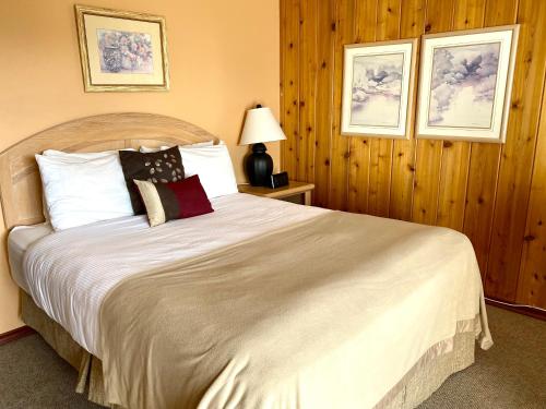 - une chambre dotée d'un grand lit avec des draps et des oreillers blancs dans l'établissement Rocky Mountain Springs Lodge, à Radium Hot Springs
